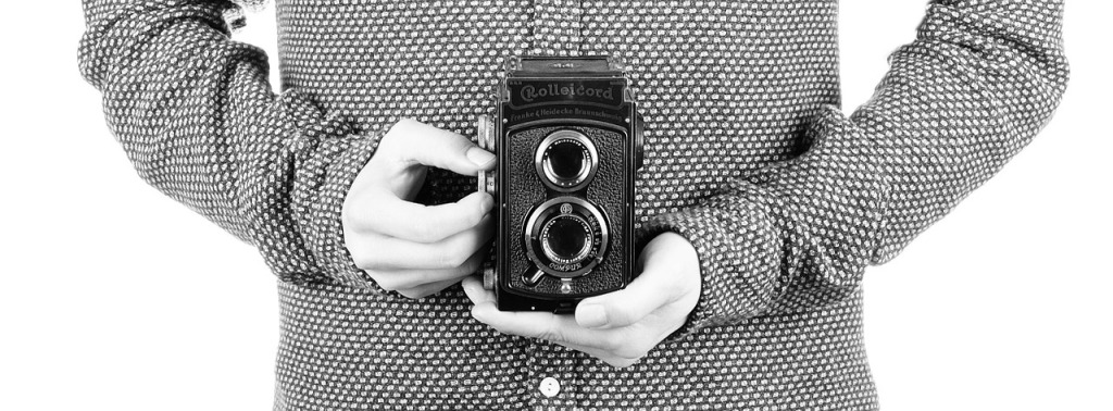 A waist-level shot of a man holding an old-fashioned camera.