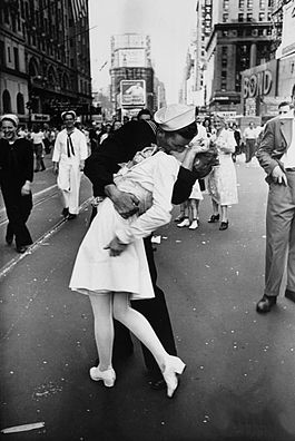 Famous photograph of a sailor kissing a nurse in Times Square. The sailor is wearing a dark uniform and the nurse is wearing all-white. 
