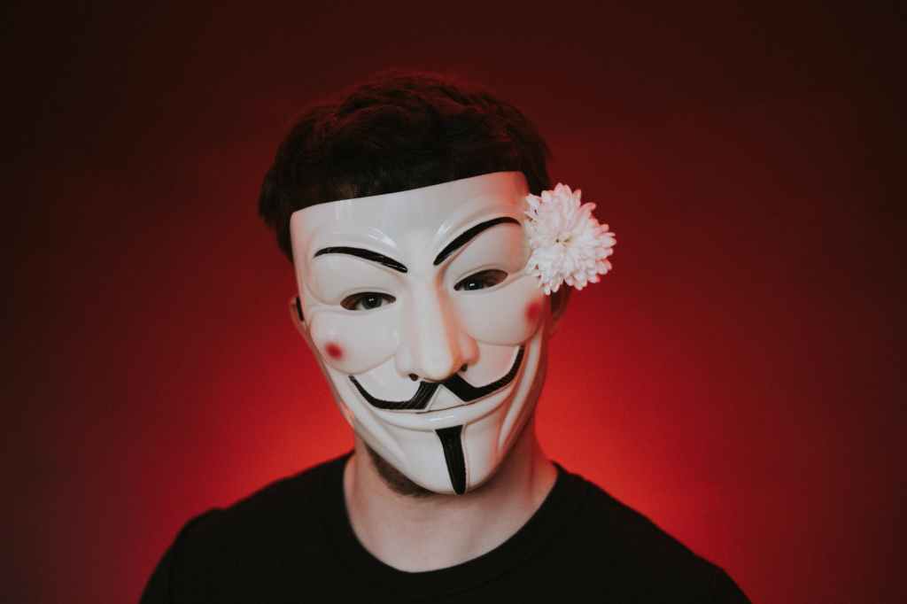male agitator in anonymous mask with blossoming flower